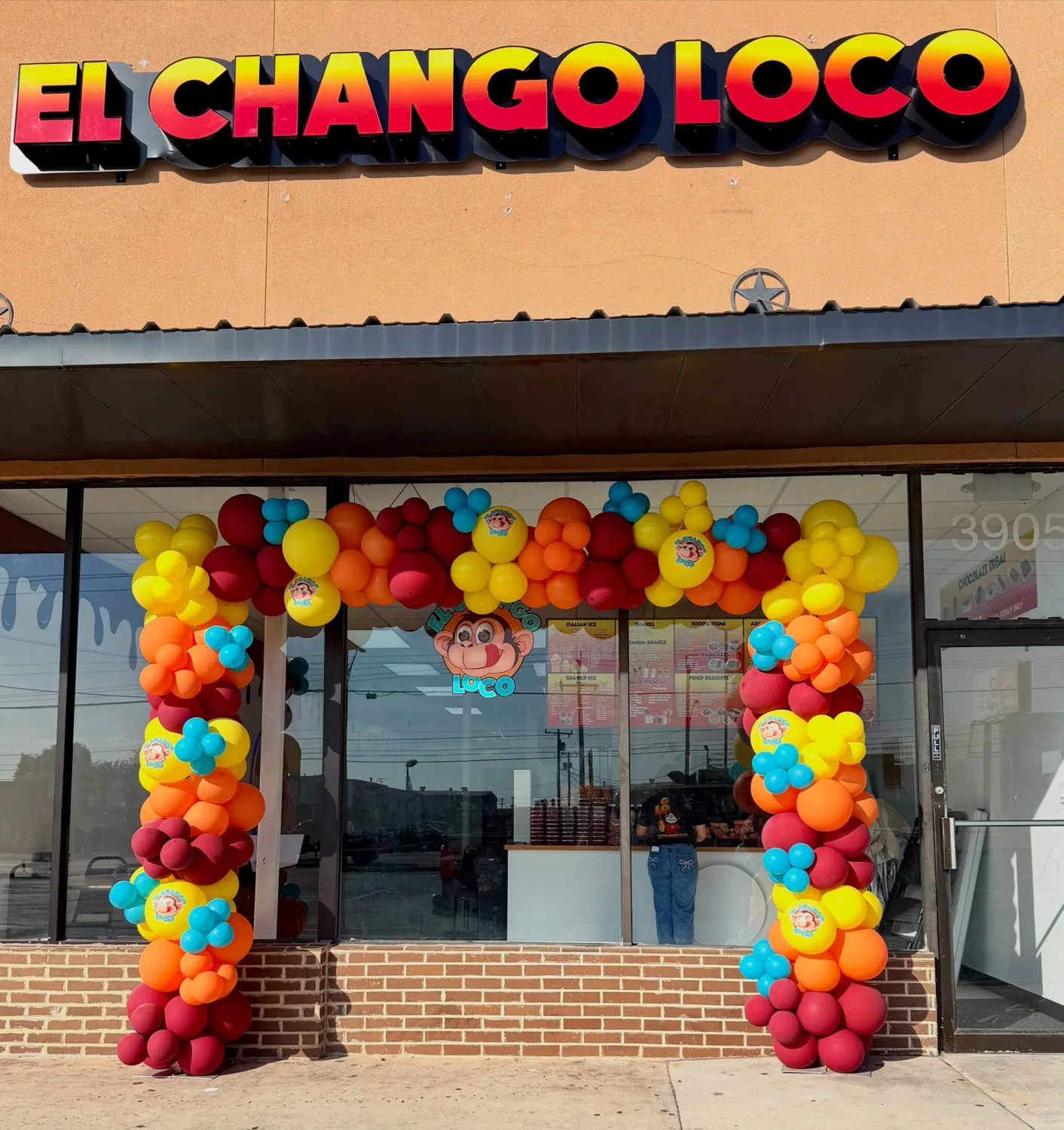 Vibrant orange, red, yellow and turquoise balloon arch decorating the El Chango Loco storefront