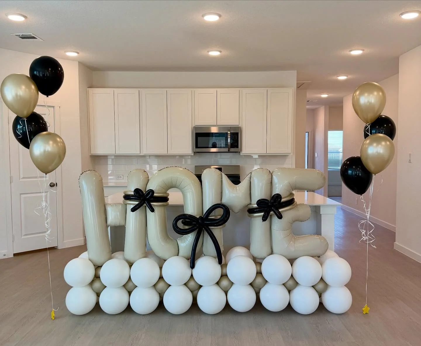 Elegant ivory Welcome Home balloon arrangement with black bows